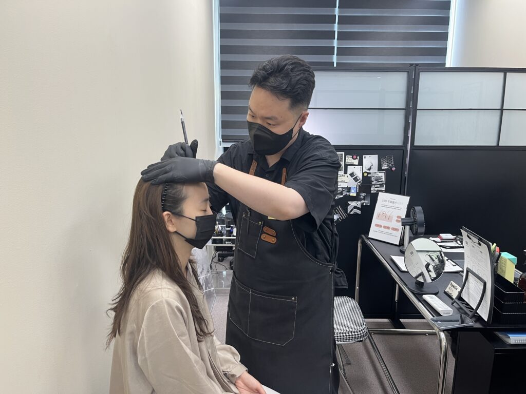 시술 전 얼굴 비율을 보며 헤어라인 디자인을 직접 그리는 모습