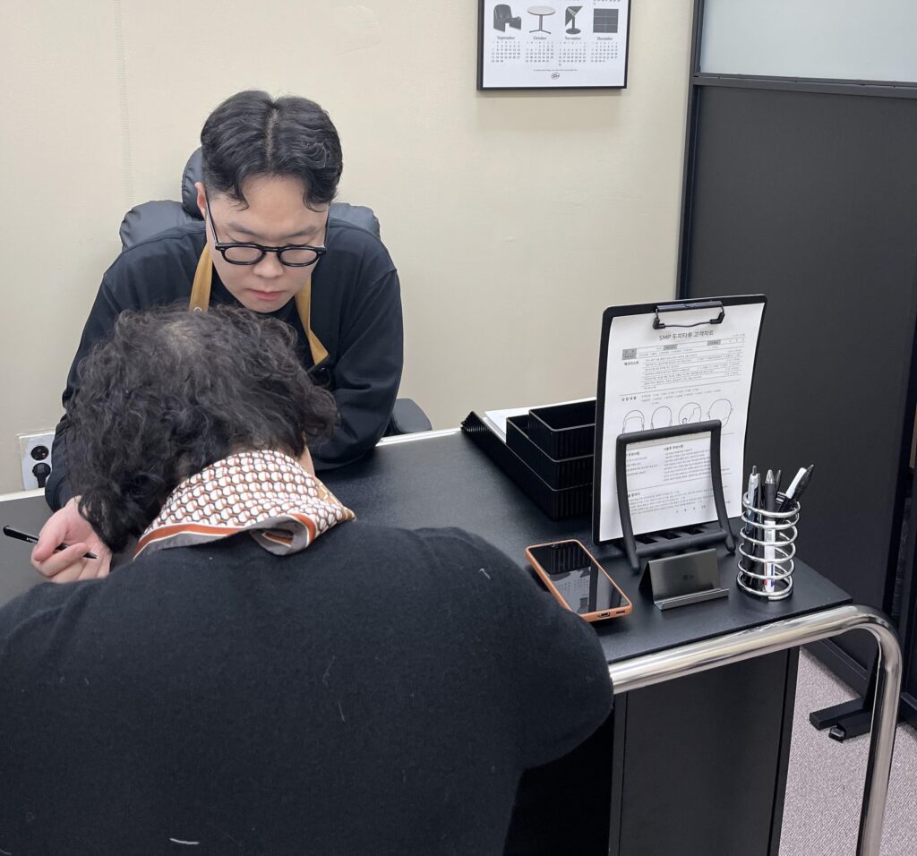 상담실에서 두피 상태를 함께 보며 탈모두피문신 계획을 설명하는 모습